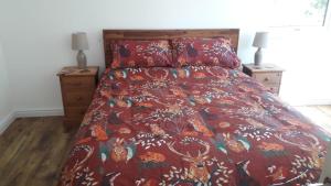 a bed with a red comforter and two night stands at Torgoyle Cottage in Inverness