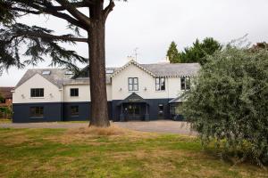 uma grande casa branca com uma árvore em frente em The Charlton Boutique Hotel em Cheltenham