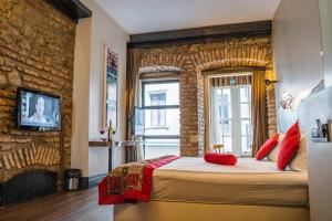 una camera da letto con un muro di mattoni e un letto con cuscini rossi di West Pera Hotel a Istanbul
