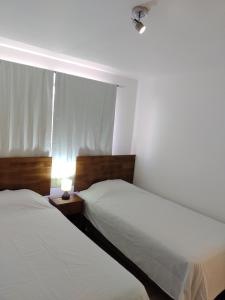 2 Betten in einem Schlafzimmer mit Fenster und Lampe in der Unterkunft DepartoCasa1 Premium in Arica