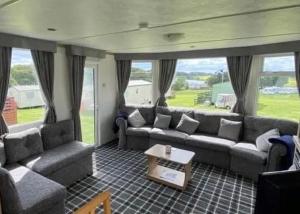 a living room with couches and a table and windows at TL083 - 2 Bedrooms indoor pool Loch Views fishing Golf Riding Shooting Water Sports 15 min drive to beaches PASSES NOT INCLUDED Most Activities Will Not Be Available Out Of Season Please Check Before Booking in Newton Stewart