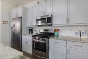 a kitchen with white cabinets and a stainless steel refrigerator at Holy City Charm - Mins to Dtwn - Beach Shem Creek in Charleston +26 photos