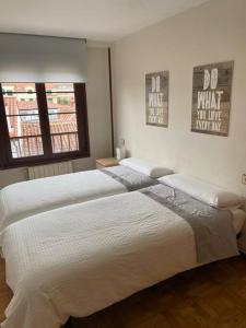 ein großes weißes Bett in einem Schlafzimmer mit zwei Fenstern in der Unterkunft Piso 3 habitaciones, centro de Colombres hasta 8 personas in Colombres