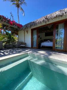 a villa with a swimming pool and a bedroom at Tiki Pool's Bungalows in Fortim