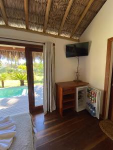 1 dormitorio con 1 cama, TV y puerta corredera de cristal en Tiki Pool's Bungalows en Fortim