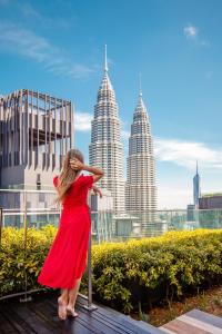 a woman in a red dress is looking at the city at Star Suites KLCC in Kuala Lumpur