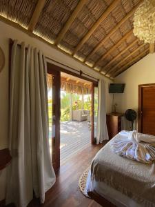 a bedroom with a bed and a sliding glass door at Tiki Pool's Bungalows in Fortim