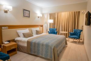 une chambre d'hôtel avec un lit et deux chaises bleues dans l'établissement Patalya Lakeside Resort Hotel, à Golbası