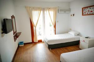 a room with two beds and a tv and a window at Parva Port in Alacati