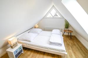 a bedroom with a white bed in a attic at Ferienhaus 16 "Gut Tossens" in Tossenserdeich