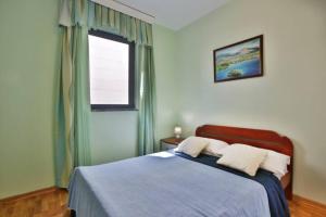 a bedroom with a bed with blue sheets and a window at Plava Vila Beach Apartments Sveti Stefan in Sveti Stefan