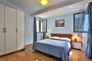 a bedroom with a bed with blue walls and wooden floors at Plava Vila Beach Apartments Sveti Stefan in Sveti Stefan