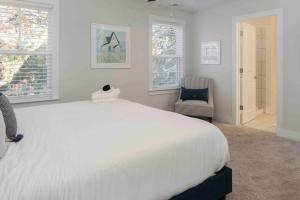 ein weißes Schlafzimmer mit einem großen Bett und einem Stuhl in der Unterkunft Spacious Charleston - 6 mins to beach & Downtown in Charleston