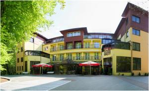 ein großes Gebäude mit roten Sonnenschirmen davor in der Unterkunft Okulski Grand Rozewie Pokoje i Apartamenty in Jastrzębia Góra