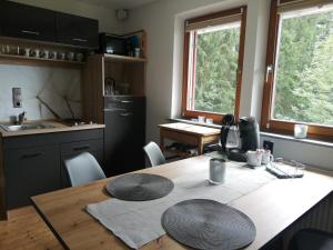 een keuken met een houten tafel met stoelen en een keuken met ramen bij 1 ZI Appartement Zauberwald in Bildstein