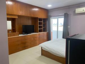 a bedroom with a bed and a flat screen tv at Hug me guesthouse in Pattaya Central