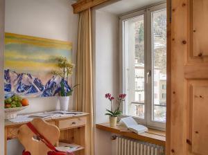 Zimmer mit einem Fenster, einem Gemälde und einem Stuhl in der Unterkunft Poschiavo Suisse Hotel in Poschiavo