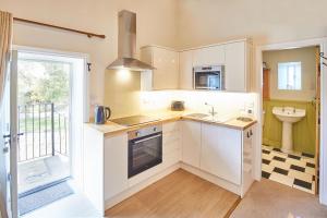 a kitchen with white cabinets and a sink at Host & Stay - The Hayloft in Ilkley