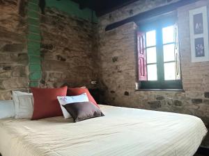 Cama en habitación con pared de ladrillo en La Castañar - La Vallicuerra Casas Rurales, en Mieres