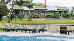 un complejo con piscina, sillas y una casa en Forest Hill Hotel, en Arusha