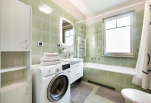 a washing machine in a bathroom with a sink and a tub at Ursus Pleasant Apartment in Warsaw