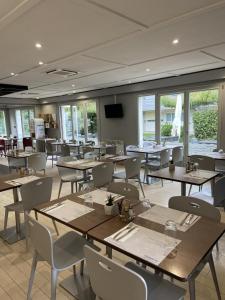 uma sala de jantar com mesas, cadeiras e janelas em Campanile Creil - Villers-Saint-Paul em Villers-Saint-Paul