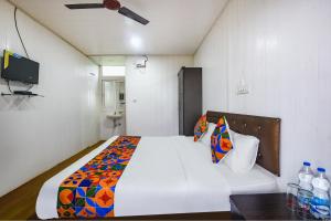 een slaapkamer met een wit bed en een kleurrijke deken bij FabExpress Vincy Palace, Mandrem Beach in Arambol