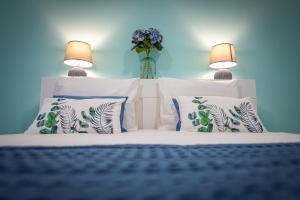 ein Bett mit weißen Kissen und eine Vase mit Blumen in der Unterkunft Dimore Italiane - Boutique Apartments in Corralejo