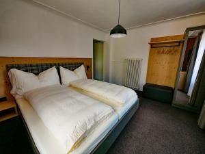 a bedroom with a large bed with white sheets at Hotel Restaurant Rätia in Filisur