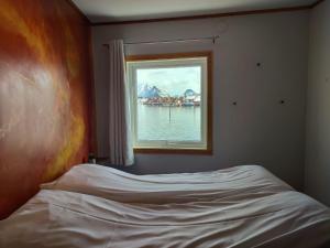 a bed in a bedroom with a window at Fish factory -The real Lofoten experience in Ballstad