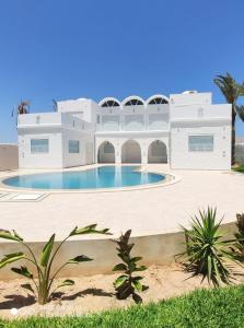 a building with a swimming pool in front of it at Villa La Palmeraie d'Arkou, grande piscine in Arkou