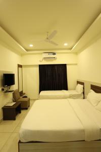 a hotel room with two beds and a television at Hotel Sigma Suites in Bangalore