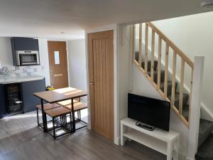 a kitchen and dining room with a table and a television at Fig Cottage Holiday Home in Whitecroft