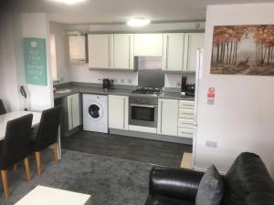 a kitchen with white cabinets and a living room at Beautiful 2 bed apartment with Parking and Wifi and 3 Smart TV's in Great Oakley