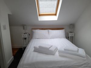 a white bed with three towels on top of it at Fig Cottage Holiday Home in Whitecroft