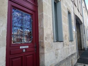 una puerta roja en el lateral de un edificio en Studio confortable, en Rochefort