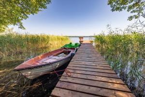 a boat sitting on a dock next to the water at Domek Całoroczny Jaśkowa Chata Leleszki 30 dom 4 in Leleszki