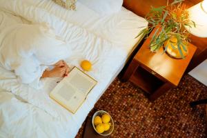 a person laying on a bed with a book and a bowl of fruit at Regina in Druskininkai