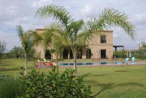 una palmera frente a una casa con piscina en La Kasbah Aalma D'or, en Najem