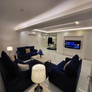 a living room with blue couches and a tv at Jamal Royal Apartments in Medina