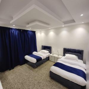 two beds in a room with blue curtains at Jamal Royal Apartments in Medina