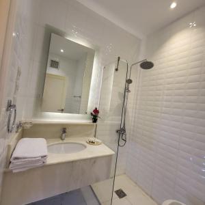 a white bathroom with a sink and a mirror at Jamal Royal Apartments in Medina