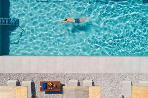 Rodostamo Hotel & Spa- Adults Friendly في كومينو: شخص يسبح في الماء في مسبح