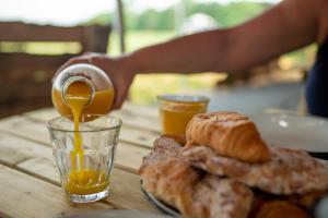 a table with a plate of bread and orange juice at Wild Meadow, Lodge Farm, East Raynham in Fakenham