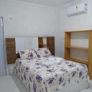 a bedroom with a bed with purple flowers on it at Mila chalé in Cruz