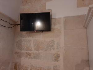 TV de pantalla plana colgada en una pared de ladrillo en Il Vico, en Lecce