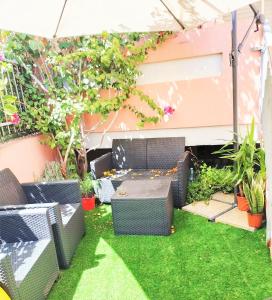 een kleine tuin met gras en stoelen en een parasol bij Bougainvillea Bank in Monserrato