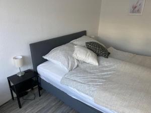 Una cama con sábanas blancas y almohadas. en Kleines Apartment in Siegburg-Kaldauen en Siegburg