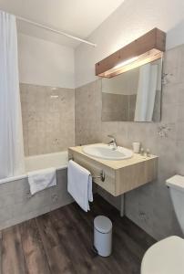a bathroom with a sink and a tub and a mirror at Terminus Hôtel des 3 Vallées in Moutiers