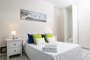 a white bedroom with a bed with colorful pillows at Casa Jolatero Ventana al Charco in Arrecife